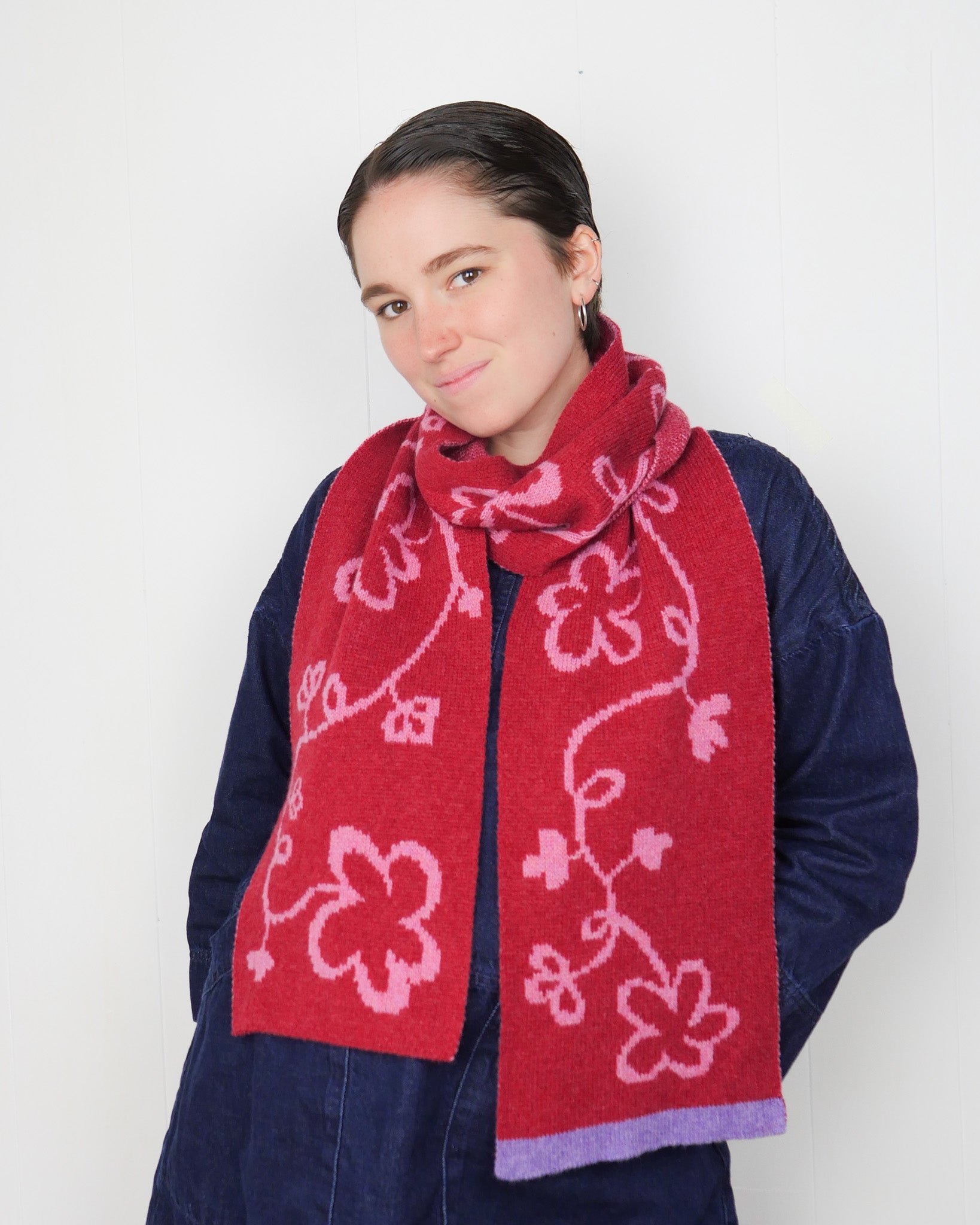 Person wearing a red floral patterned scarf against a white background