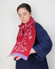 Woman wearing a red scarf with pink floral patterns against a white background