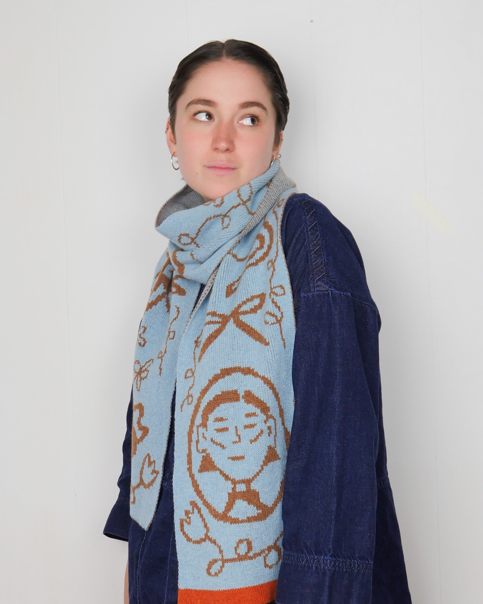 Person wearing a blue scarf with a pattern on a white background