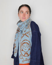 Person wearing a blue scarf with a pattern on a white background