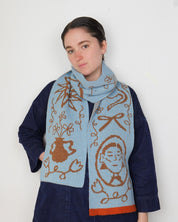 Woman wearing a blue scarf with brown patterns against a white background