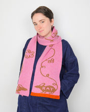 Person wearing a pink scarf with brown rar designs on a white background